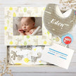 Baby gift set with grey personalised baby bib, photo frame, and blanket featuring animal patterns on a wooden surface.