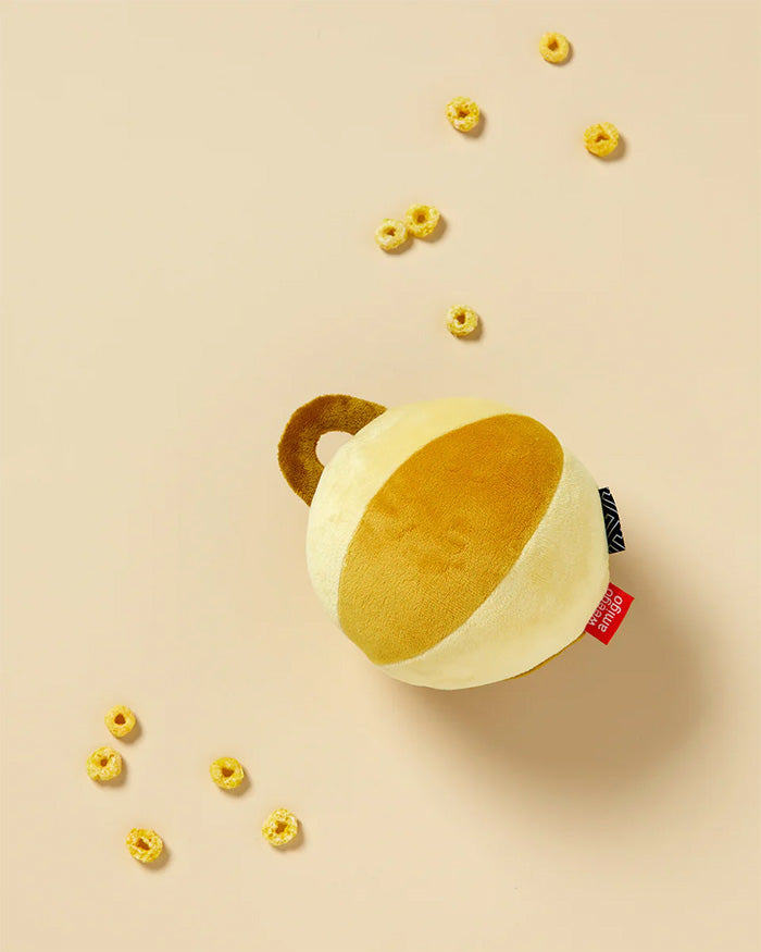 Yellow plush toy with a red tag on a beige background