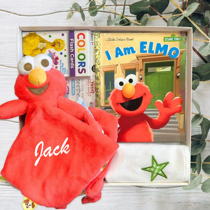 Red Elmo plush toy with 'Jack' embroidered, Sesame Street book, and flashcards in a box.