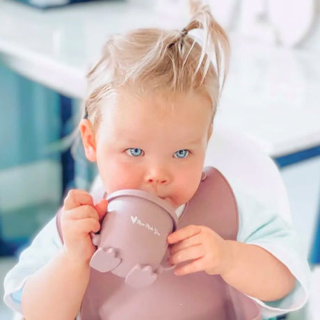 Child holding a pink cup with a blurred background