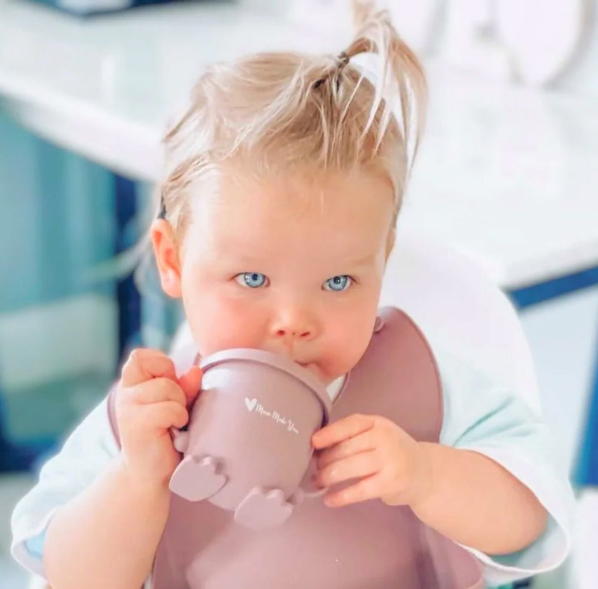 Child holding a pink cup with a blurred background