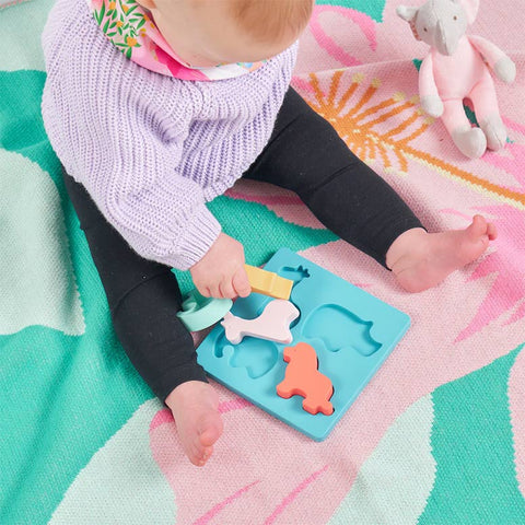 Child playing with a toy on a colorful blanket