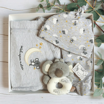 Baby koala clothing with toy in a gift box on a wooden surface