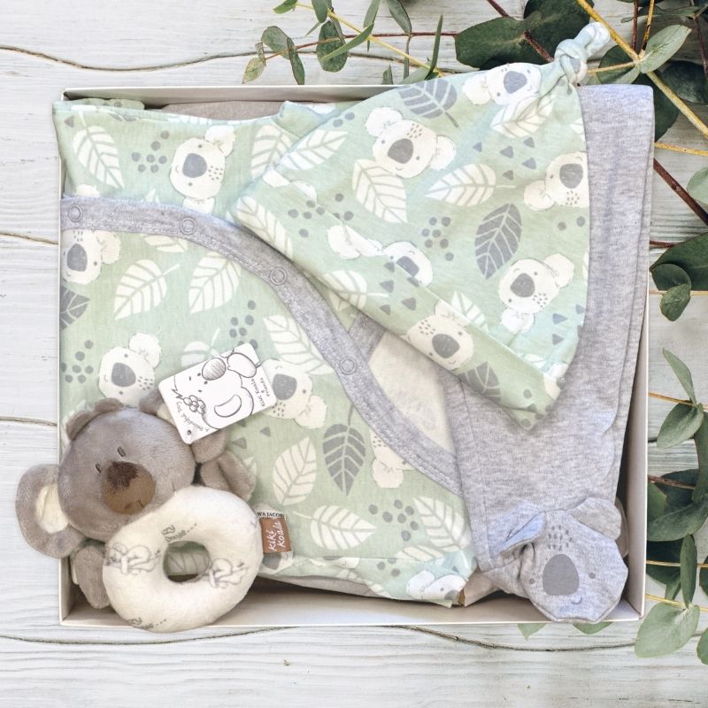 Baby koala clothing with toy in a gift box on a wooden surface