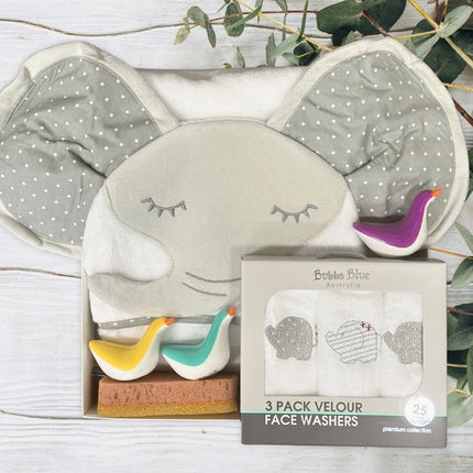 Set of three velour face washers with packaging on a wooden surface with greenery.