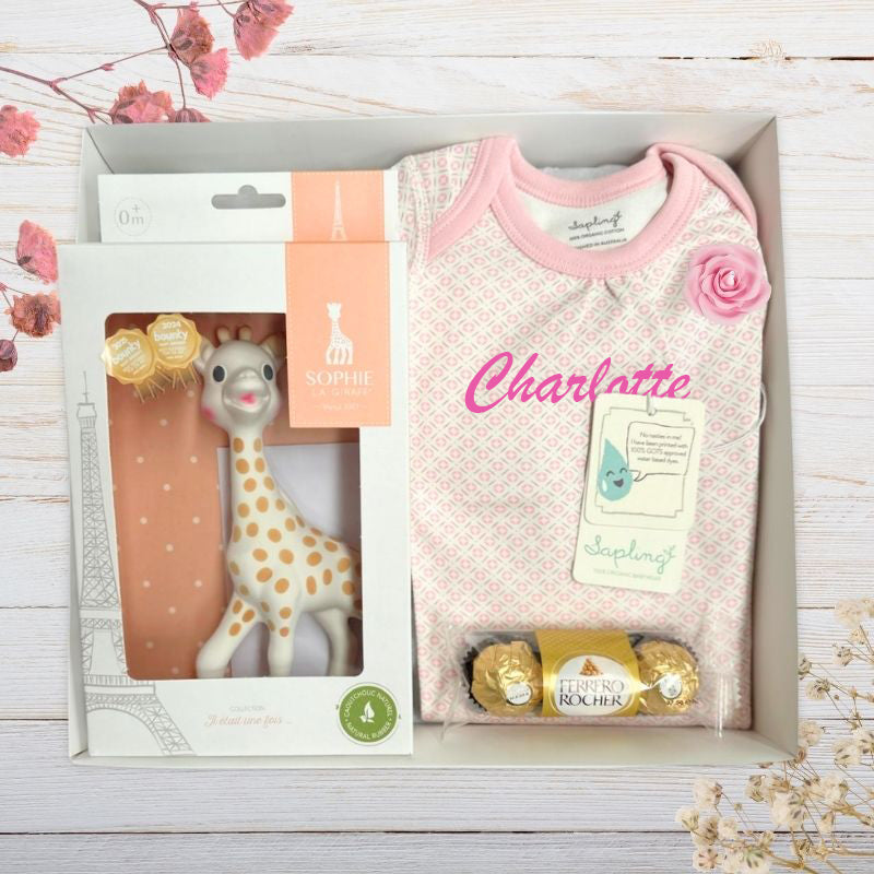 Baby gift set with sophie giraffe toy, custom name baby top in gift box on a wooden surface