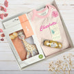 Baby gift set with sophie giraffe toy, pink top, rose , chocolates in a box on a wooden surface