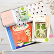 Collection of baby sophie girafe  products including a book and teether on a wooden surface.