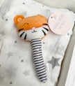 Plush tiger rattle with striped handle on a star-patterned blanket