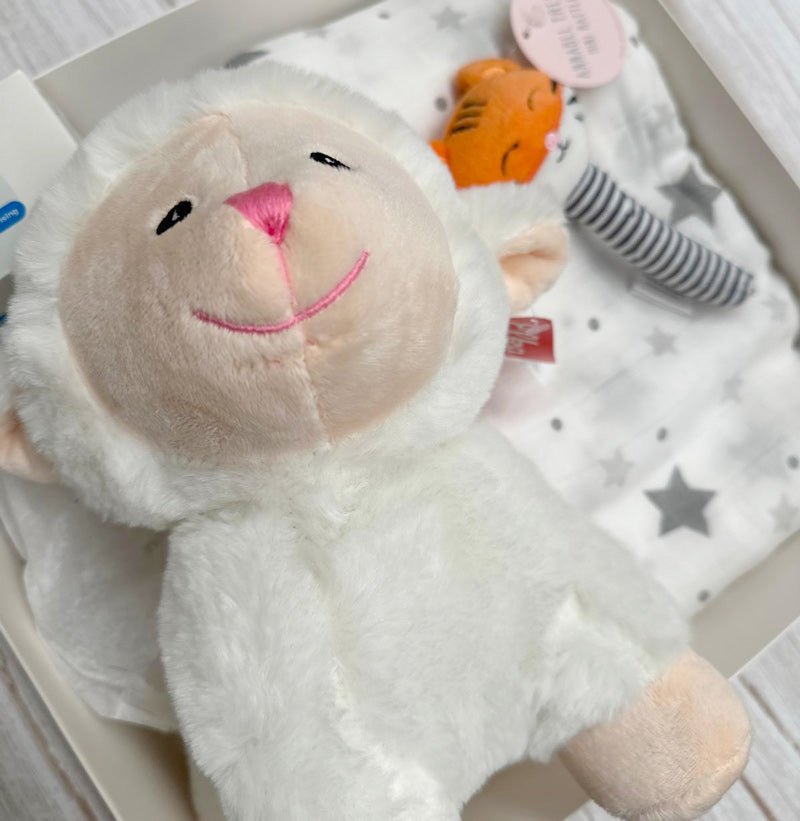 White plush lamb toy with a pink nose in gift box on a white surface