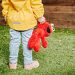 Child holding a colorful soft Elmo toy in the garden