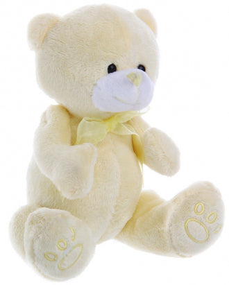 Cream-colored teddy bear with a bow on a wooden table background