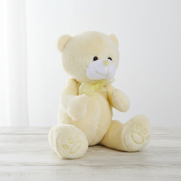 Cream-colored teddy bear with a bow on a white background