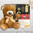 Large brown teddy bear toy and biscuits in a baby gift box.