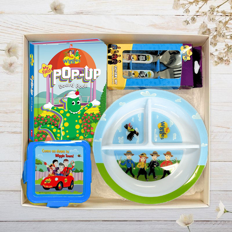 The Wiggles Children's dining set with bib, plate, and cutlery in gift box on a wooden surface