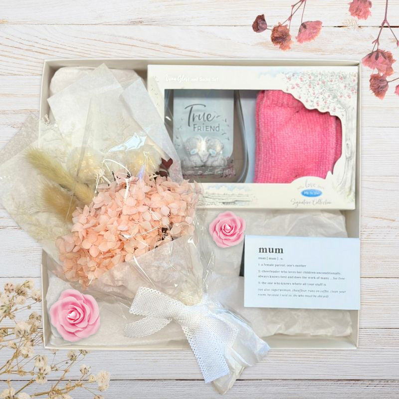 Gift set with flowers, card, and pink gifts for mum on a wooden surface