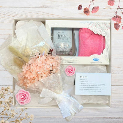 Gift set with flowers, card, and pink gifts for mum on a wooden surface