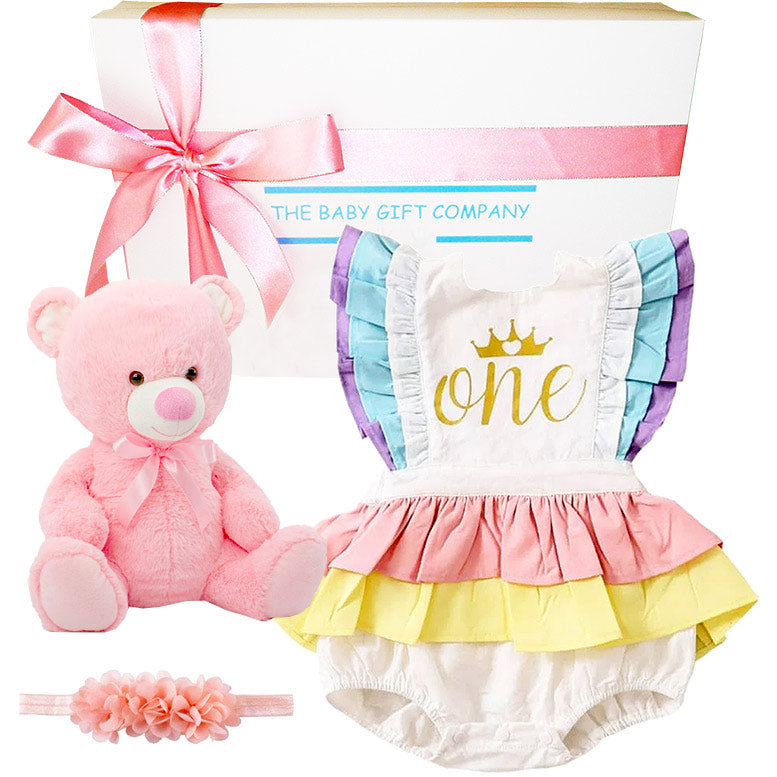 Baby gift set with pink teddy bear, colorful baby romper, and headband from The Baby Gift Company.