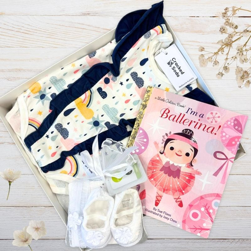 Gift box with frilly baby girl clothes , white shoes and ballerina book