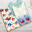 Baby bib, booties, and bibs set with elephant animal patterns in a gift box on a wooden surface