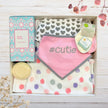 Baby gift set with cutie baby bib, burp cloth, and soap in a gift box on a wooden surface.