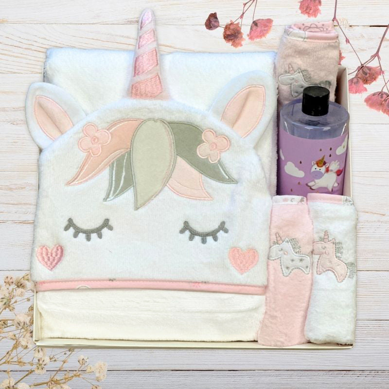 Unicorn-themed blanket with a bottle of body wash in a gift box on a wooden surface