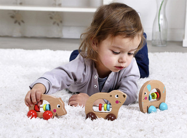 Child playing with wooden toys on a white carpet