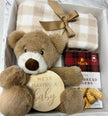 Plush teddy bear with 'We're Having a Baby' sign, checkered blanket, and Mac's bread in a gift box.