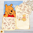 Winnie the Pooh-themed children's clothing and book on a wooden surface.