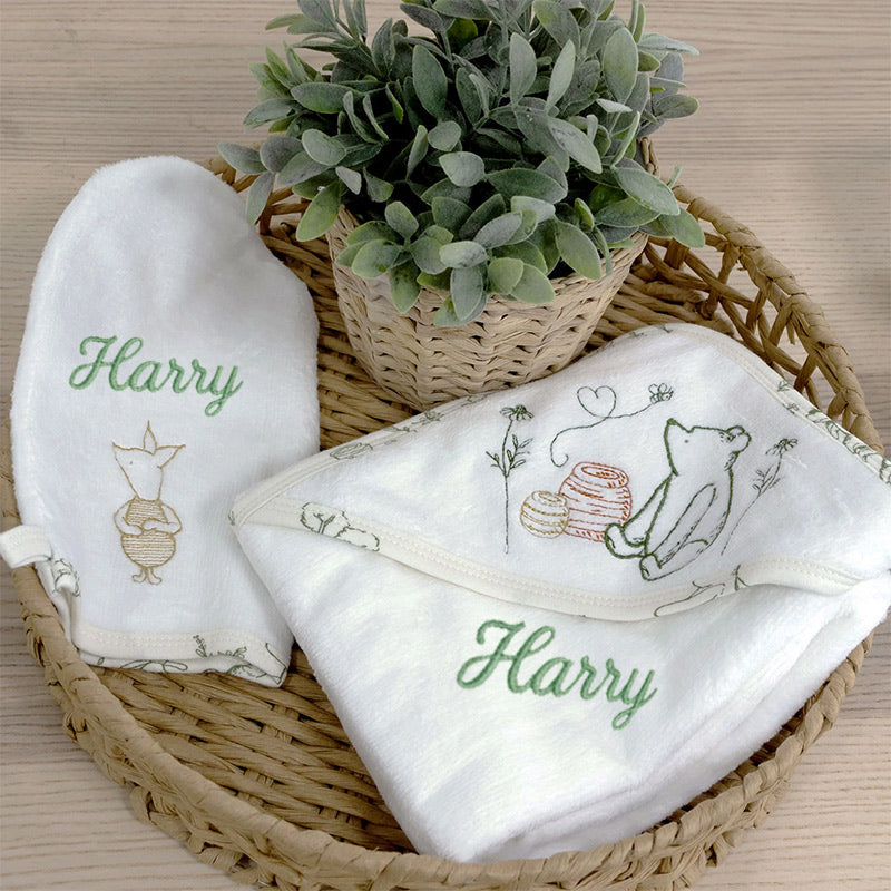 winnie the pooh baby towel set in white on a wicker basket