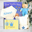 Baby gift set with teddy bear, book, and photo album on a wooden surface.