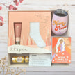 Gift set with 'Mum Power' tumbler, socks, and other items in gift box on a wooden surface.