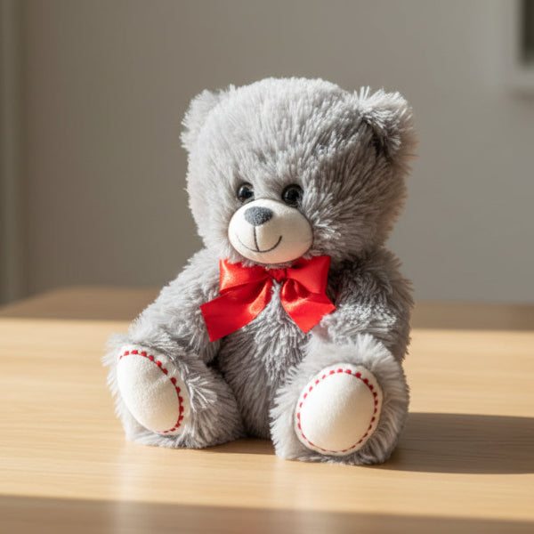 Gray teddy bear with a red bow on a white background