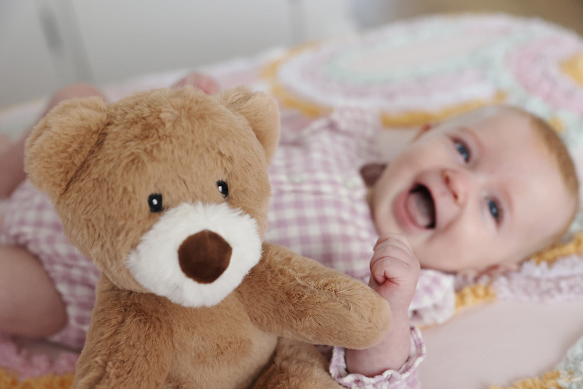 Smiling baby girl and a brown teddy bear