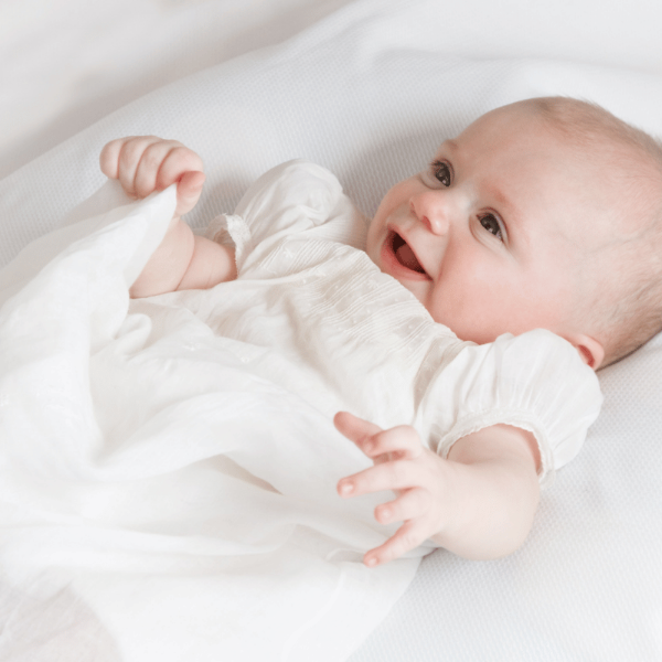 Baby in a white onesie lying on a white blanket