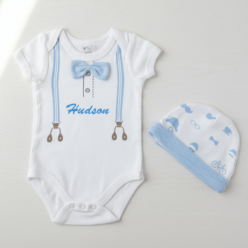 White baby onesie with blue bow tie and matching hat on a light gray background