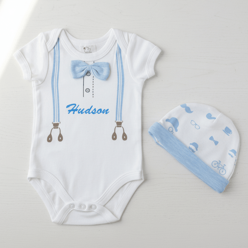 White baby onesie with blue bow tie and matching hat on a light gray background