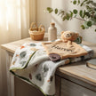 Plush toy bear with baby name on top of a baby blanket on table background