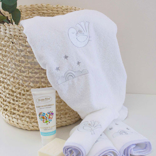 White towel with embroidery, baby lotion, and soap on a white surface