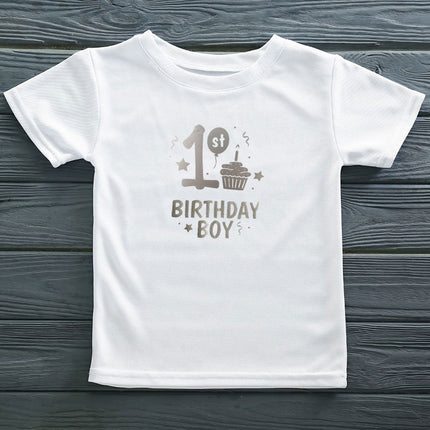 White t-shirt with '1st Birthday Boy' text on a wooden surface