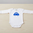 White baby onesie with a blue car design on a table