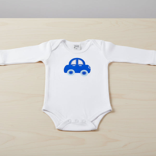 White baby onesie with a blue car design on a table