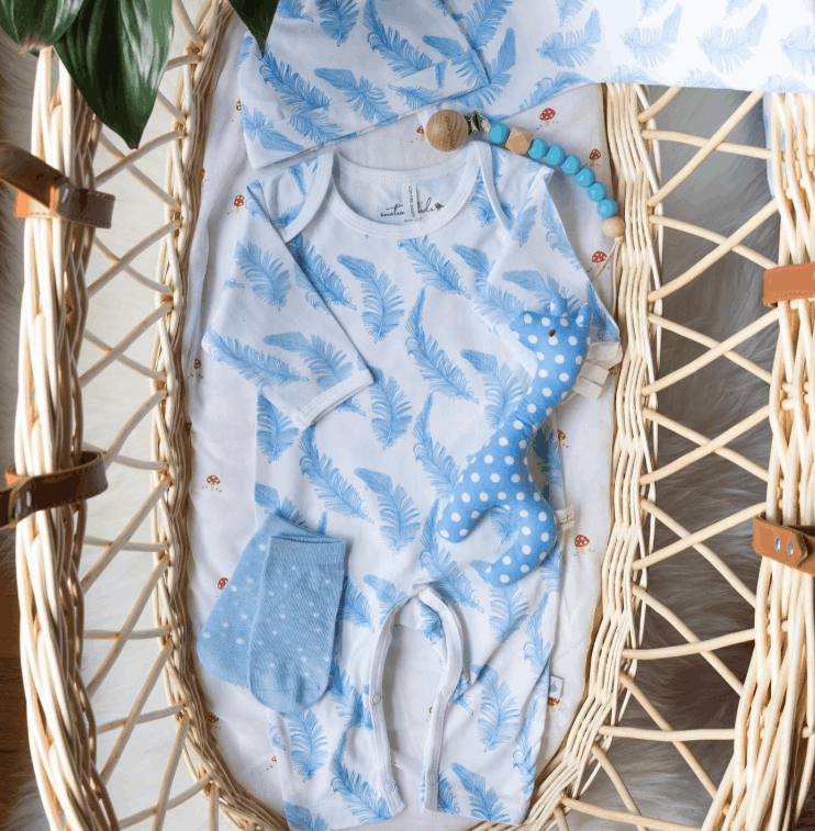 Baby outfit set with blue and white pattern on a wicker baby basket