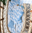Baby outfit set with blue and white pattern on a wicker baby basket