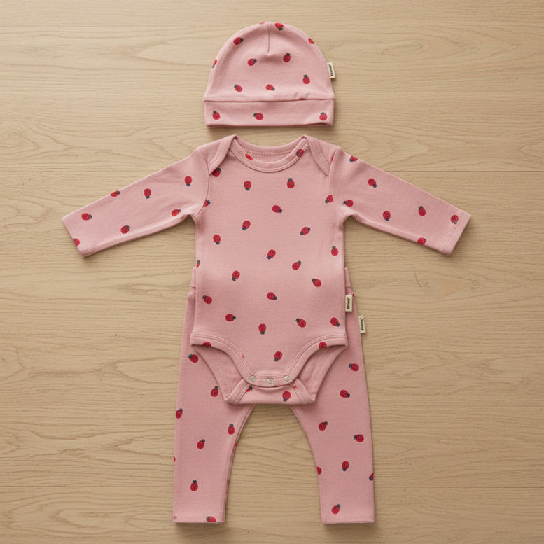 Three piece baby set in pink with 'Bonds' branding on a table background.