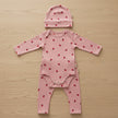 Three piece baby set in pink with 'Bonds' branding on a table background.
