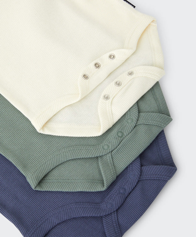 Three baby bodysuits in cream, navy, and green on a white background