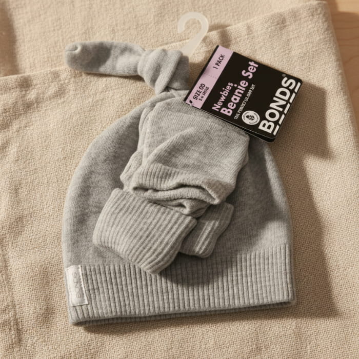 Grey baby hat with 'Bonds' label on a fabric background