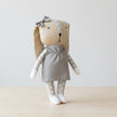 Stuffed toy rabbit with a gray dress and bow on table