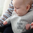 Baby wearing grey 'born in 2026' bib